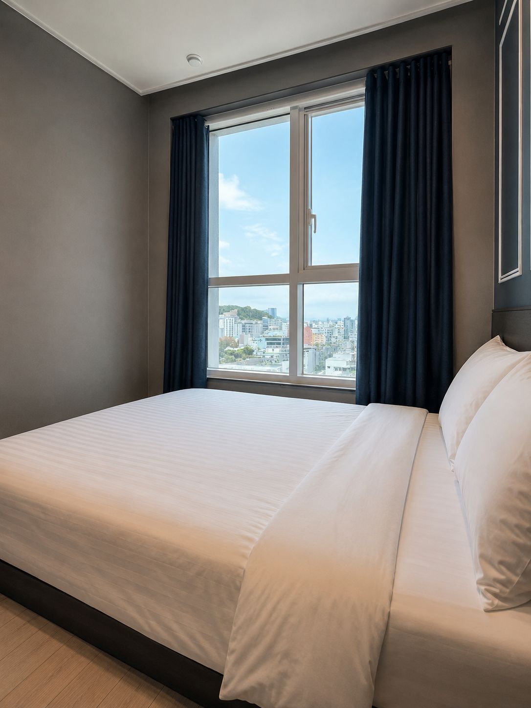 Un cuarto de hotel con un ventanal grande, una cama y vistas a la ciudad.