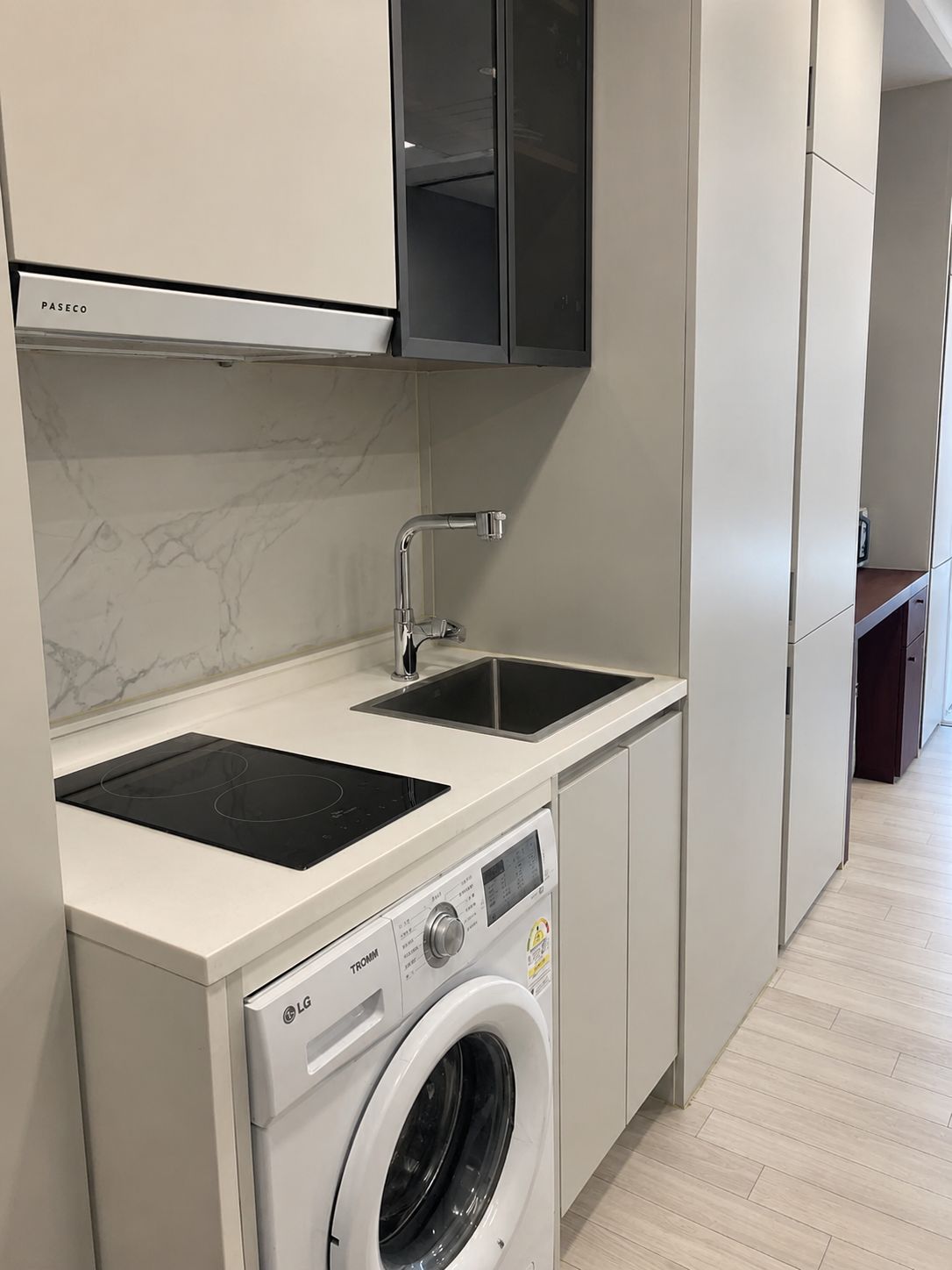 A modern kitchen with a built-in washing machine, a double sink, and a stainless steel faucet.