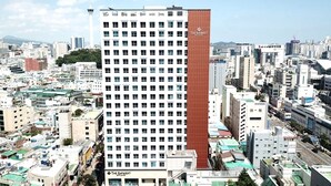 Un hotel moderno de gran altura con una fachada llamativa roja y blanca, varios pisos y vistas de la ciudad circundante.