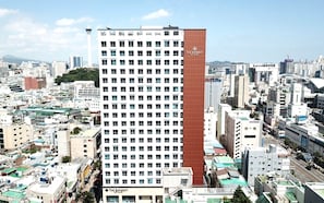 A high-rise hotel with a prominent red and white facade, multiple floors, and a view of the surrounding cityscape. - STAY NAMPO PREMIER (Busan)