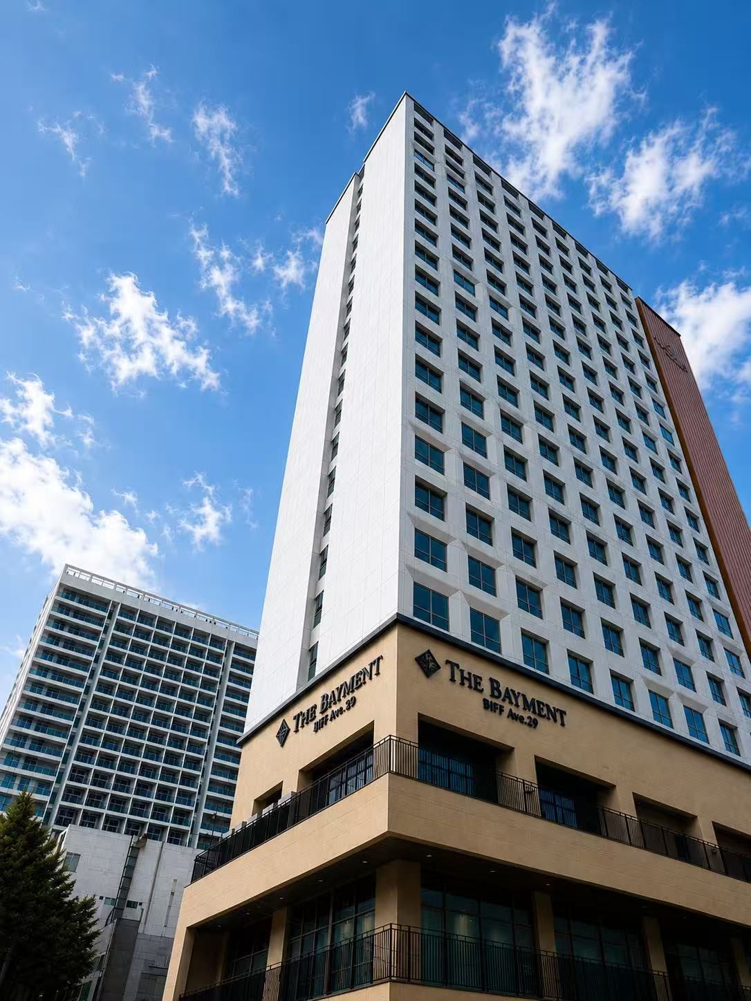 A high-rise hotel building with multiple floors, featuring a prominent sign for 'The Baymont' on the lower level.