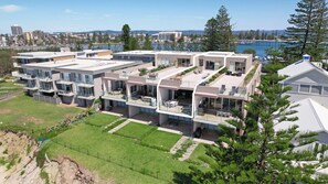 A modern multi-story residential building with multiple balconies, a flat roof, and a view of a body of water. - Paradise Penthouse Ocean Views (The Entrance North)