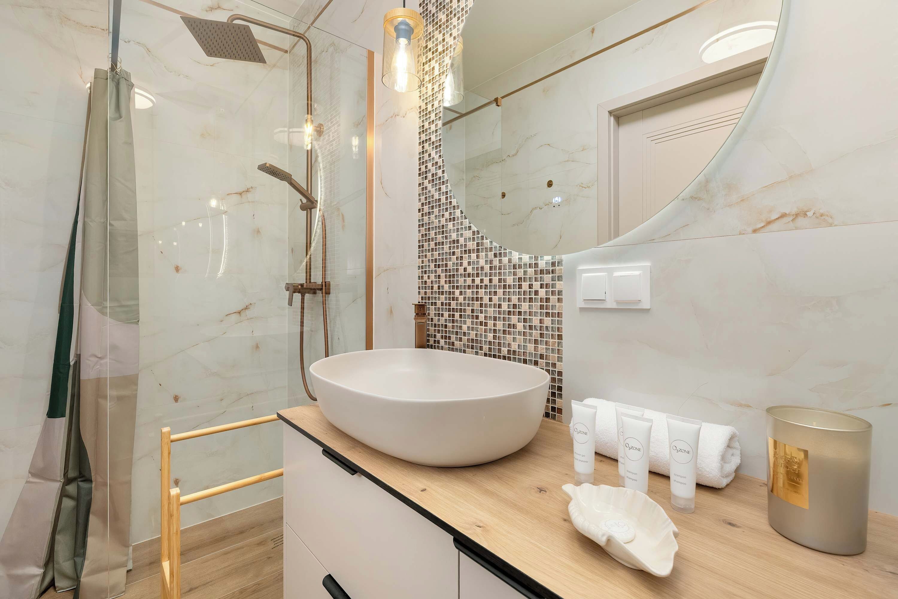 Ein modernes Badezimmer mit einem großzügigen Waschbecken, einer Duschkabine aus Glas und einer gefliesten Spritzwand.