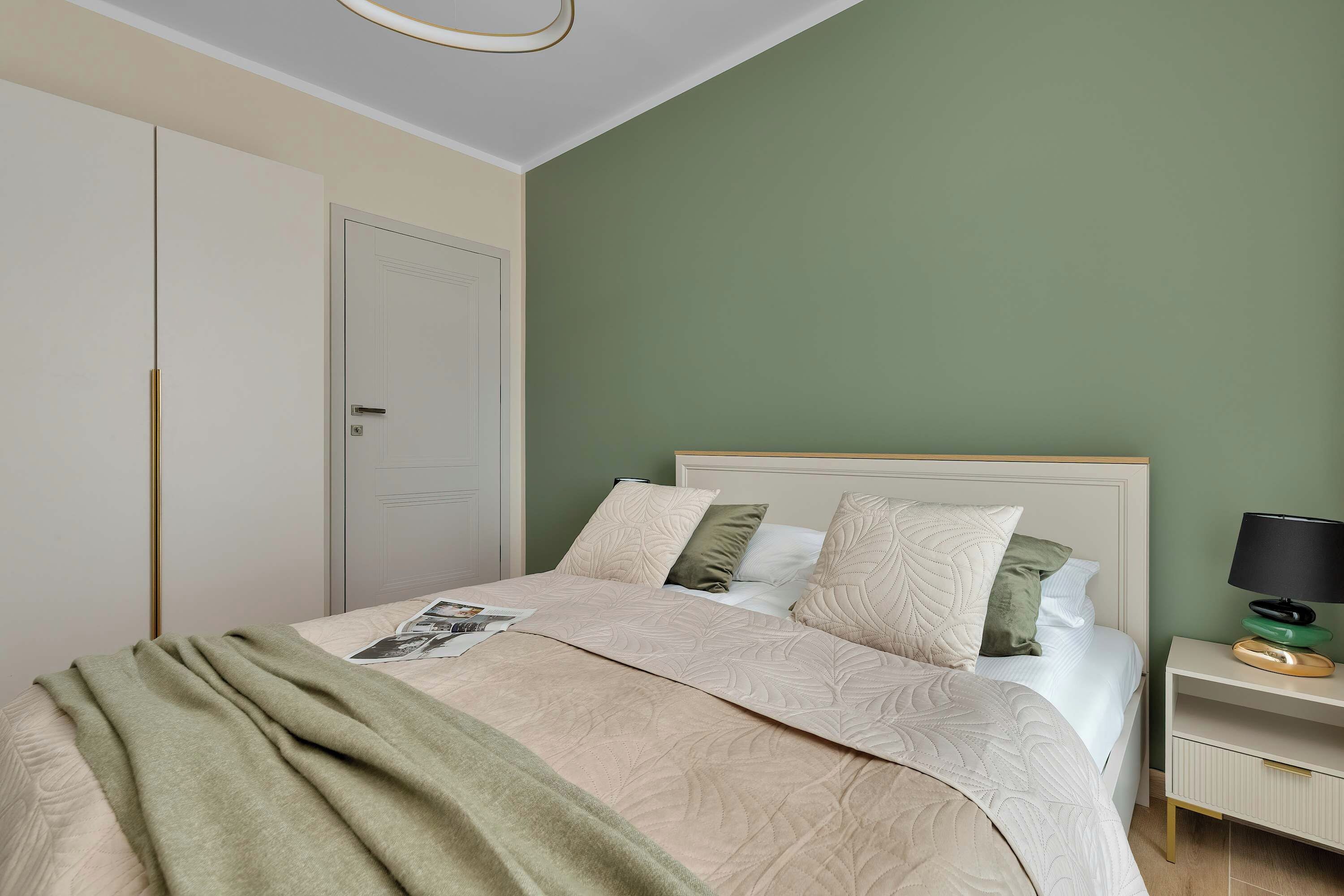 Een slaapkamer met een bed, nachtkastje, lamp en een kledingkast.