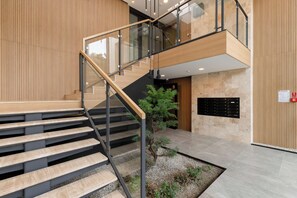 Un interior moderno con una escalera, paneles de madera y un pequeño jardín interior.