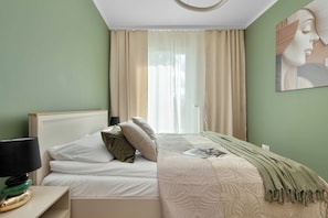 Ein Schlafzimmer mit einem Bett, Kissen, einer Lampe, einer Decke und einem Bild an der Wand.