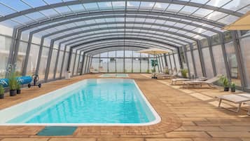 Ein überdachter Pool mit Liegestühlen und Blumentöpfen.