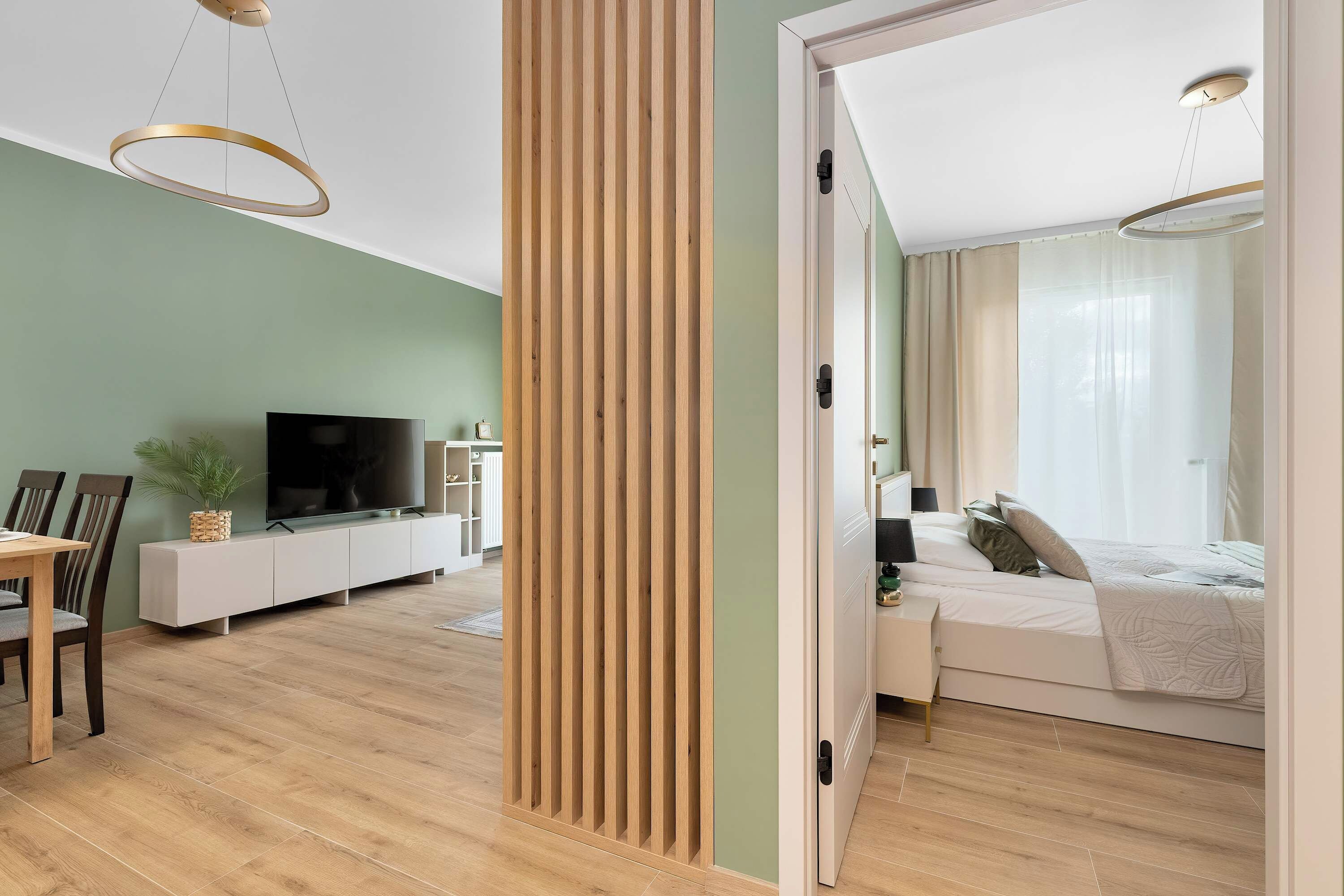 A modern bedroom with a bed, bedside table, and a TV in the living area.