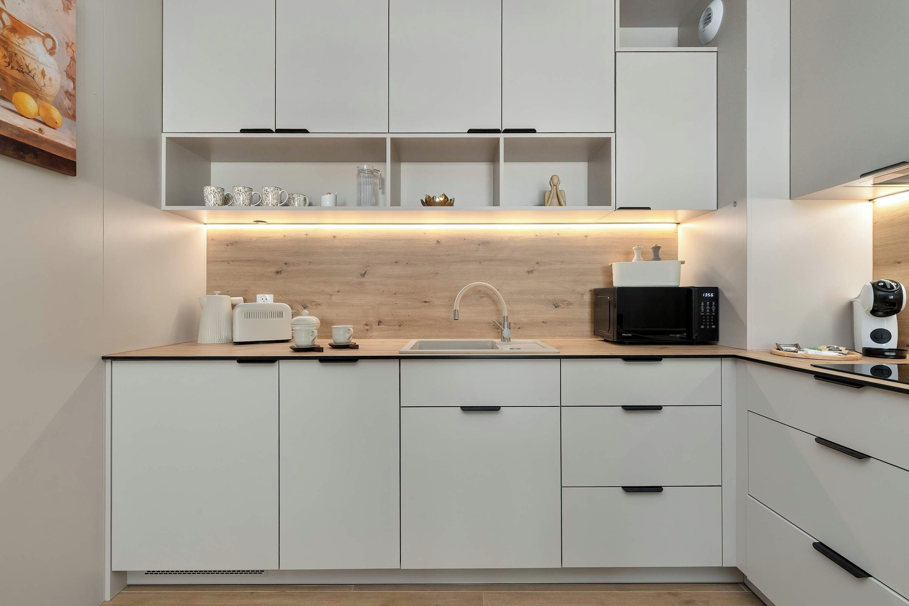 Eine moderne Küche mit weißen Schränken, einer Holzarbeitsplatte, einem Spülbecken, einer Mikrowelle und einem Toaster.