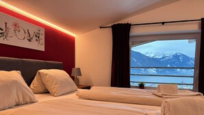 Et hotelværelse med en seng, et sengebord, en lampe, et vindue med udsigt til bjerge og en væg med et 'LOVE'-skilt.