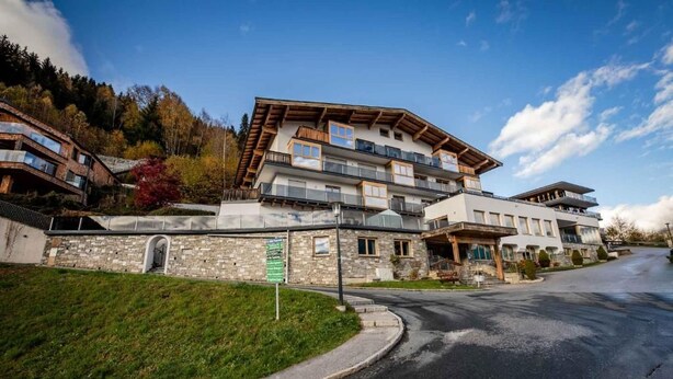 Et hotel med flere etager, en stenfassade, balkoner og udsigt til et bjerrelandskab.