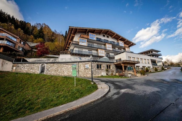 Een meerlaags hotel met een stenen gevel, balkons en uitzicht op een bergachtig landschap.