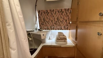 Un baño pequeño con lavamanos, una pila de toallas y un papel tapiz estampado.