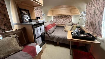 Ein kompaktes Wohnmobil-Interieur mit zwei Betten, einer Küchenzeile und einem kleinen Tisch.