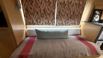 Un lit compact doté d’une tête de lit, d’un oreiller et d’une couverture à rayure rouge.