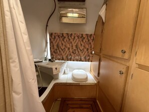 Een kleine badkamer met toilet, wastafel en een handdoek aan de muur.