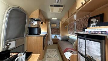 A compact RV interior with a kitchenette, a bed, and a small living area.