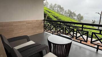 Un espacio de estar techado al aire libre con muebles de mimbre y una mesa, con vista a un paisaje montañoso.