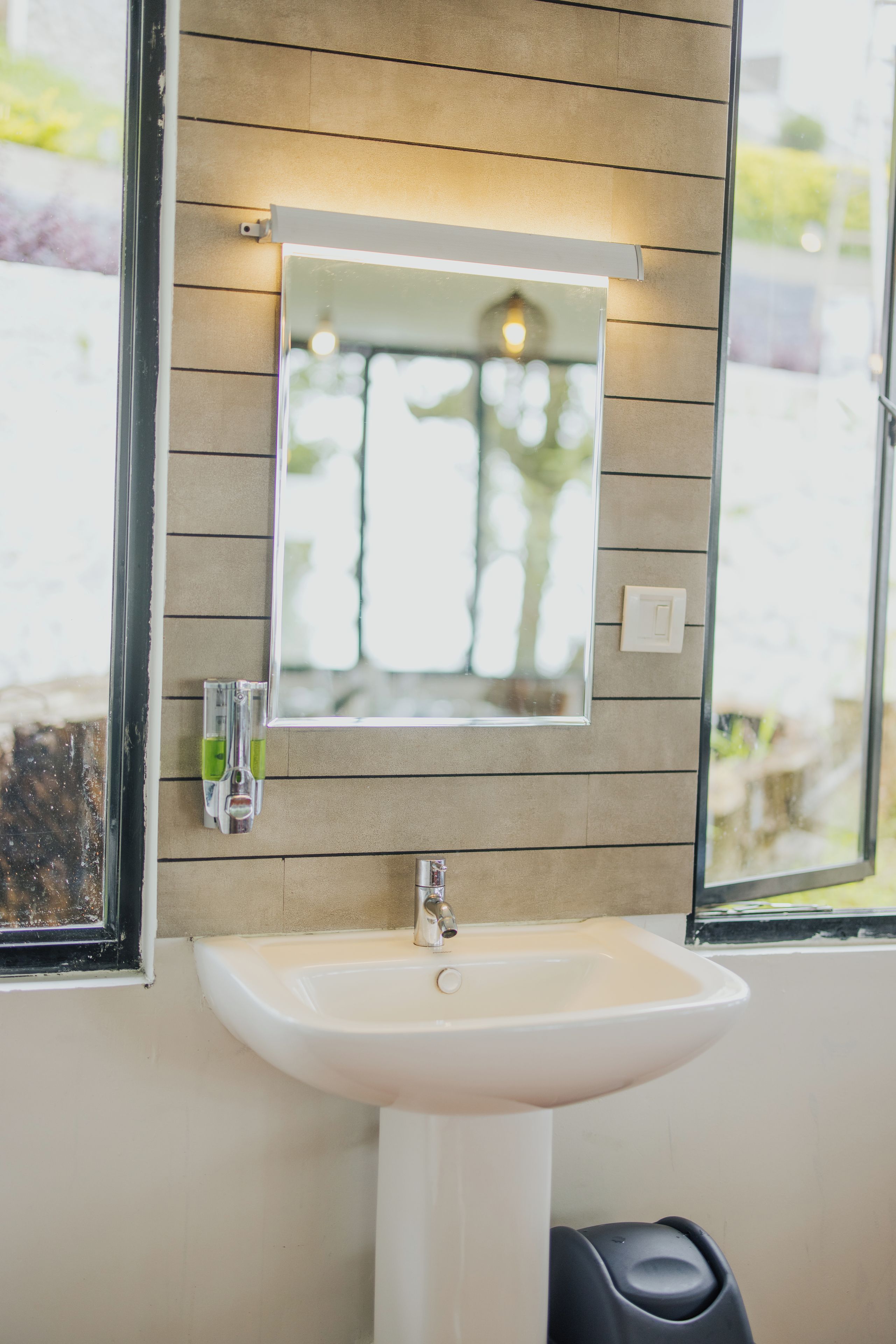 A bathroom with a white sink, a mirror, and a window.