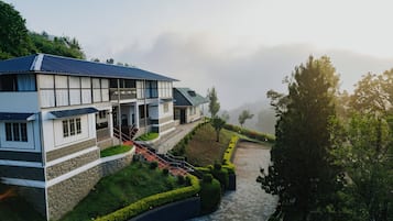 Ein zweistöckiges Gebäude mit einem Balkon, einer Steinmauer und einem gepflasterten Weg zum Eingang.