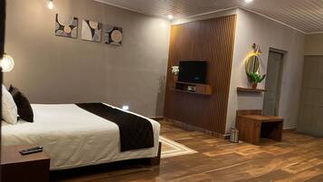 Een moderne slaapkamer met een bed, een televisie bevestigd aan een houten paneelwand, een nachtkastje en een bijzettafeltje.