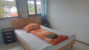 Camera da letto con un letto, una testiera in legno, un comodino, una cassettiera e una finestra vista case.