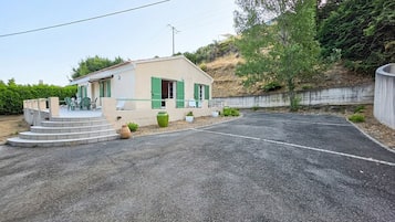 A small building with a paved driveway, steps leading to the entrance, and a green door.