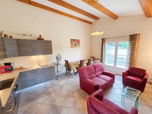 A modern kitchen with built-in appliances, a dining area with a table and chairs, and a seating area with a sofa and armchairs. - Villa Terrasse Olmeta-di-tuda Proche St Florent (Olmeta-di-Tuda)