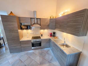 A modern kitchen with built-in appliances, a microwave, a stove, and a sink. - Villa Terrasse Olmeta-di-tuda Proche St Florent (Olmeta-di-Tuda)