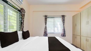 Una camera d'albergo con un letto, un armadio e due finestre con tende.