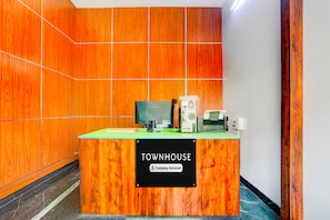 Ein Empfangsschalter mit Schild, der auf einen firmeneigenen Service hinweist, ein Computer, ein Drucker und eine Kaffeemaschine.