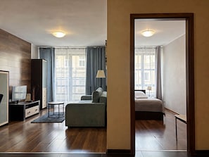 Una habitación de hotel moderna con sofá, cama, televisor y escritorio.