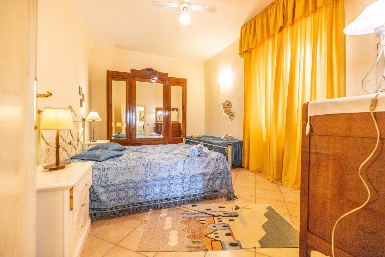 A bedroom with a bed, a dresser, a mirror, a lamp, and a rug.