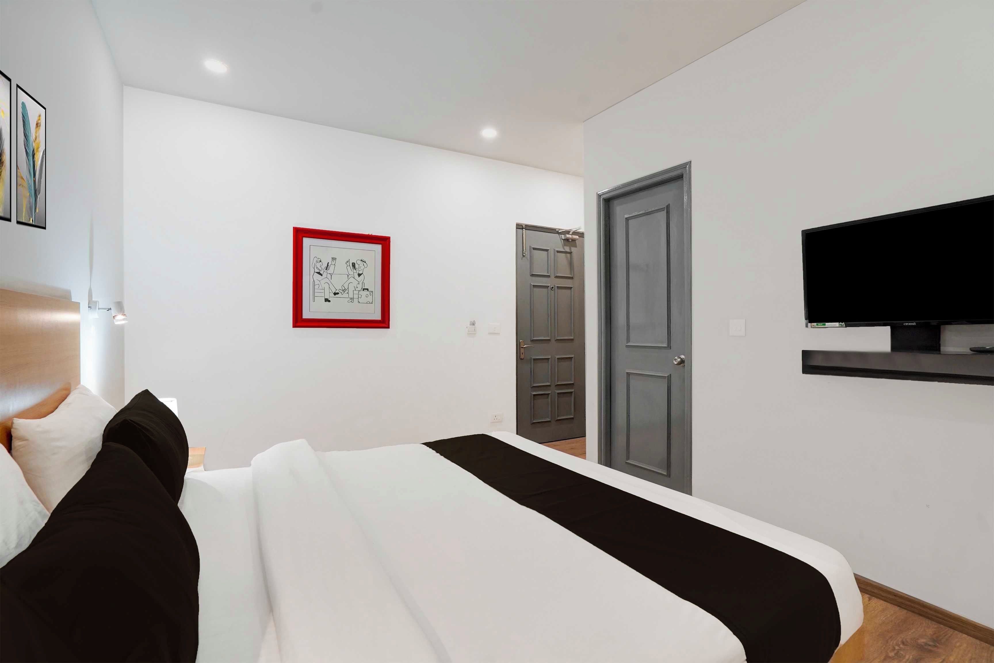 A modern bedroom with a bed, a television mounted on the wall, and a door.