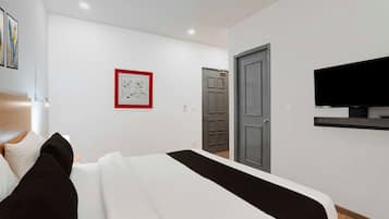A modern bedroom with a bed, a television mounted on the wall, and a door.