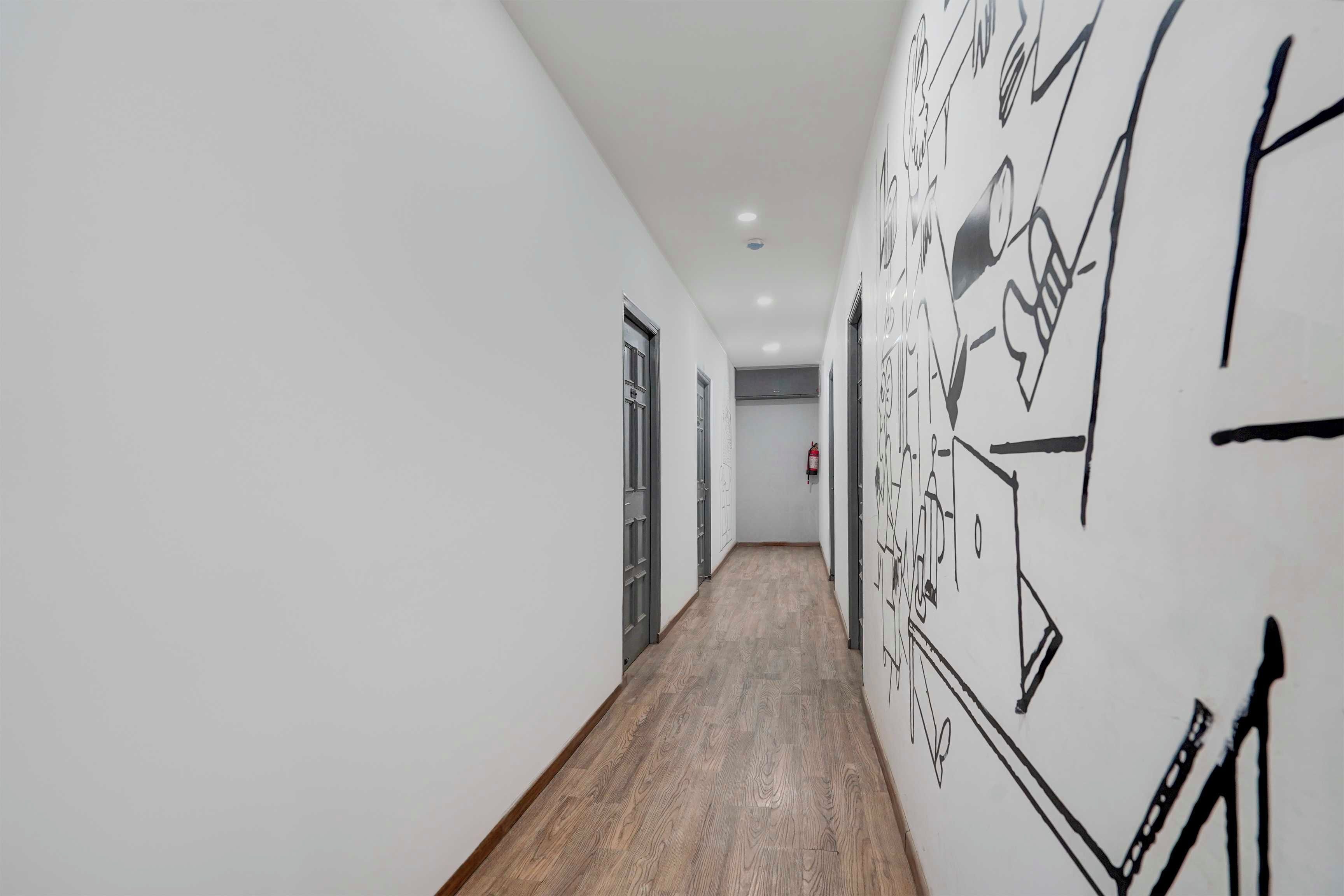 A hallway with a wooden floor, white walls, and black abstract wall art.