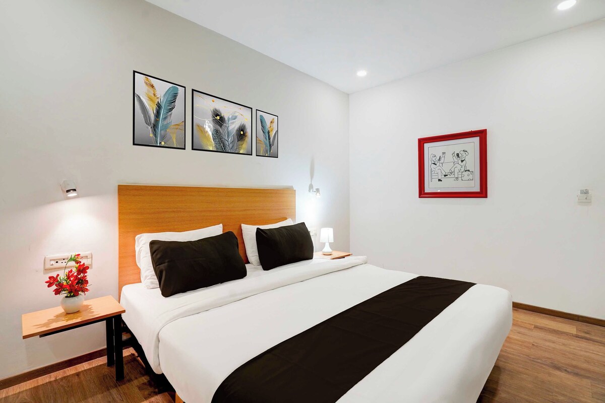 A hotel room with a bed, a nightstand, a lamp, and artwork on the walls.