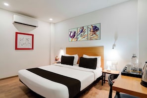 Ein Hotelzimmer mit Bett, Nachttisch, Lampe und einem Bild an der Wand.