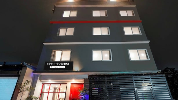 Un edificio de varios pisos con un cartel que indica 'TOWNHOUSE OAK' y 'Company-Serviced'.