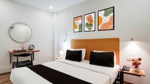 Una habitación de hotel con cama, mesita de noche, lámpara y espejo en la pared.