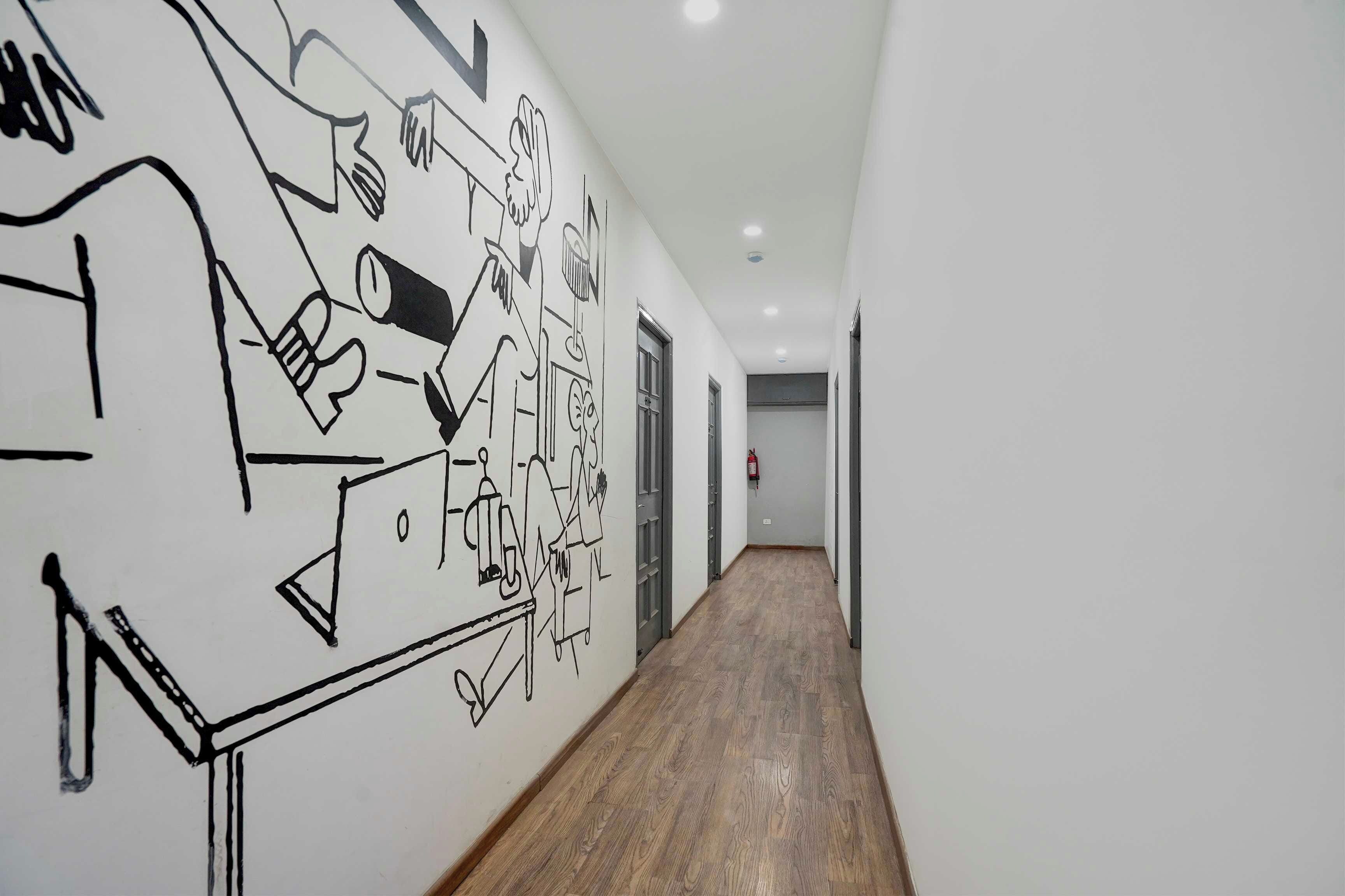 Un pasillo con suelo de madera y paredes blancas, con un mural abstracto en blanco y negro.