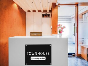 A reception desk with a sign reading 'TOWNHOUSE Company-Serviced.' - Townhouse Ramamurthy Nagar West (Bengaluru)