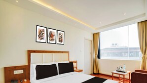 Une chambre d’hôtel avec un grand lit, une table de chevet, une chaise, une fenêtre avec des rideaux et des œuvres d’art accrochées au mur.