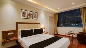 Une chambre d’hôtel avec un lit, une table de chevet, une lampe et une vue sur la ville la nuit.