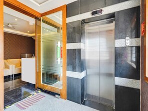 A hotel lobby with a reception desk, a glass door, and an elevator. - Townhouse Ramamurthy Nagar West (Bengaluru)