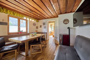 Ein Essbereich mit Holzboden, einer Bank, einem Tisch und einem Kamin.