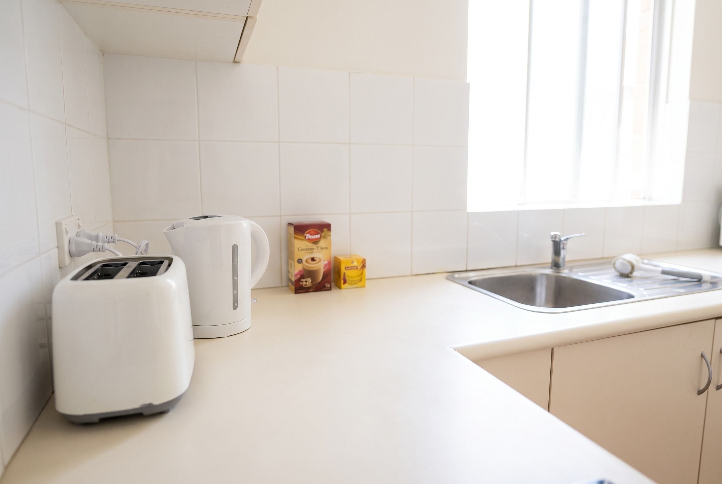 Eine Küche mit weißen Schränken, einer Spüle, einem Toaster und zwei Kaffeepackungen.