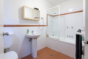 A bathroom with a toilet, sink, mirror, and shower. - Bondi Studio | 2 Min Walk to Beach, Queen Bed, Separate Kitchen (Bondi Beach)