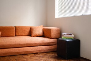 A room with a sofa and a small black ottoman. - Bondi Studio | 2 Min Walk to Beach, Queen Bed, Separate Kitchen (Bondi Beach)