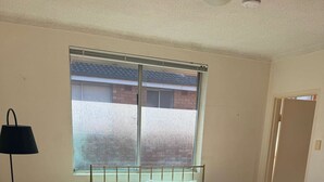 Un dormitorio con cama, ventana, lámpara de pie y puerta.